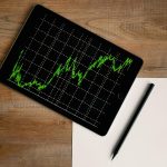 pexels-photo-187041-187041 Flatlay of an iPad displaying stock market graph on a wooden desk with a pencil and paper.